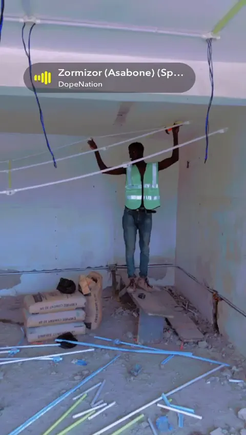 Technician working around ceiling wiring in a corporate interior