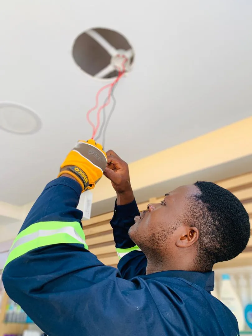 Technician checking ceiling wiring during electrical work